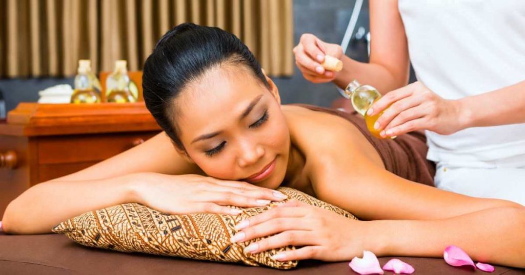 Mujer recibiendo masaje balinés relajante con aceites.