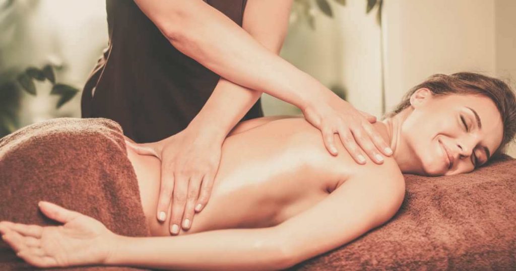 Mujer recibiendo terapia sueca en spa para la espalda con roces de mano.